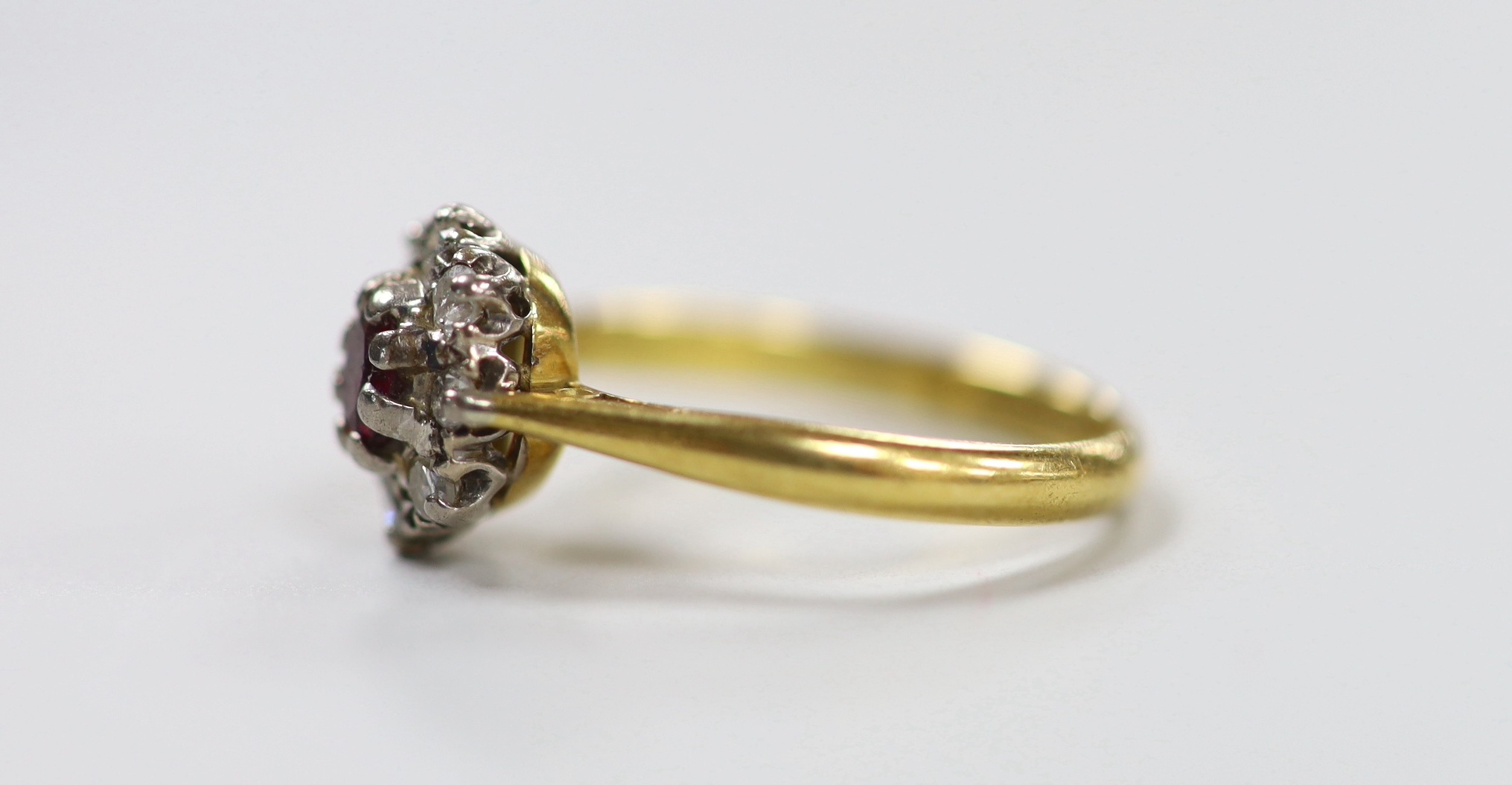 A modern 18ct gold, garnet? and diamond set oval cluster ring, size M, gross weight 3.2 grams.
